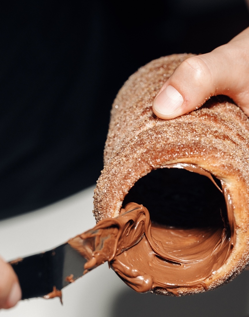 Nutella being spread inside a fresh chimney cake